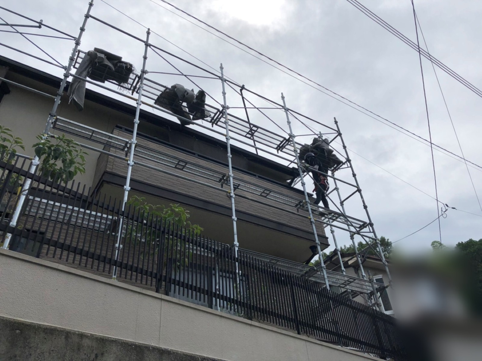 屋根の軒先の高さで足場のパイプを組み立てる職人