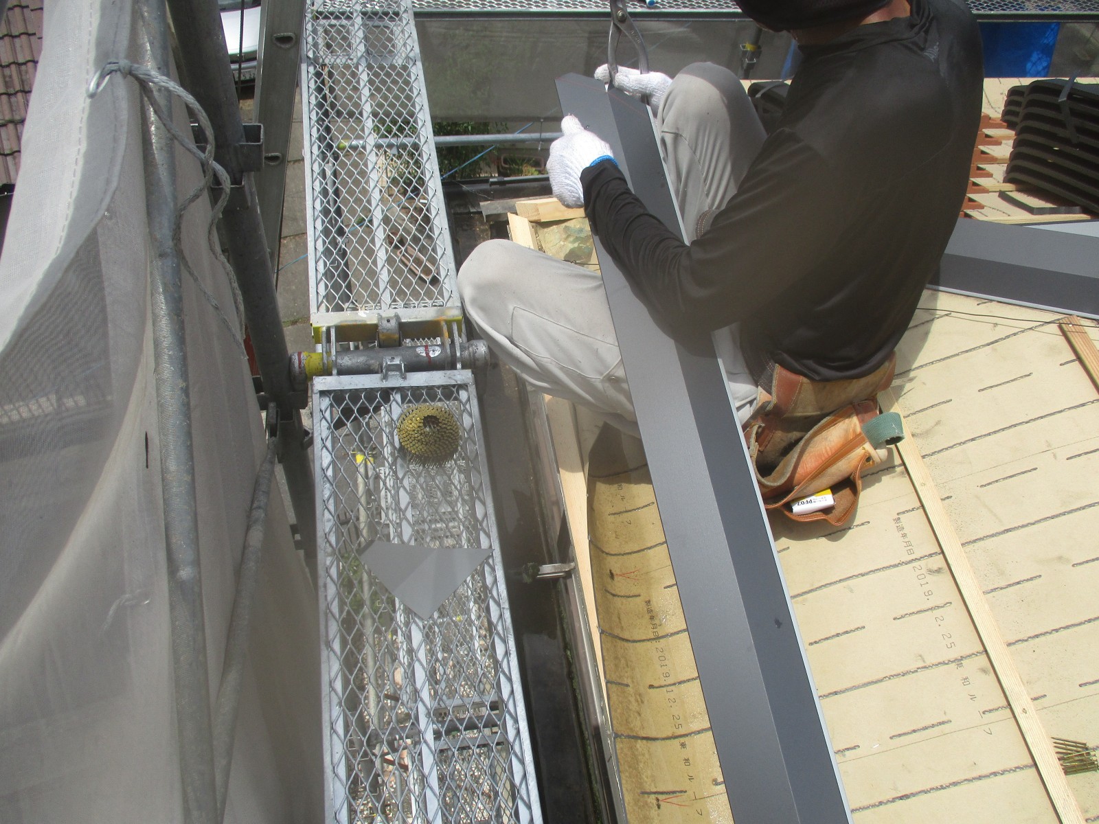 軒先に取り付ける雨水を流す金属の板を持つ職人