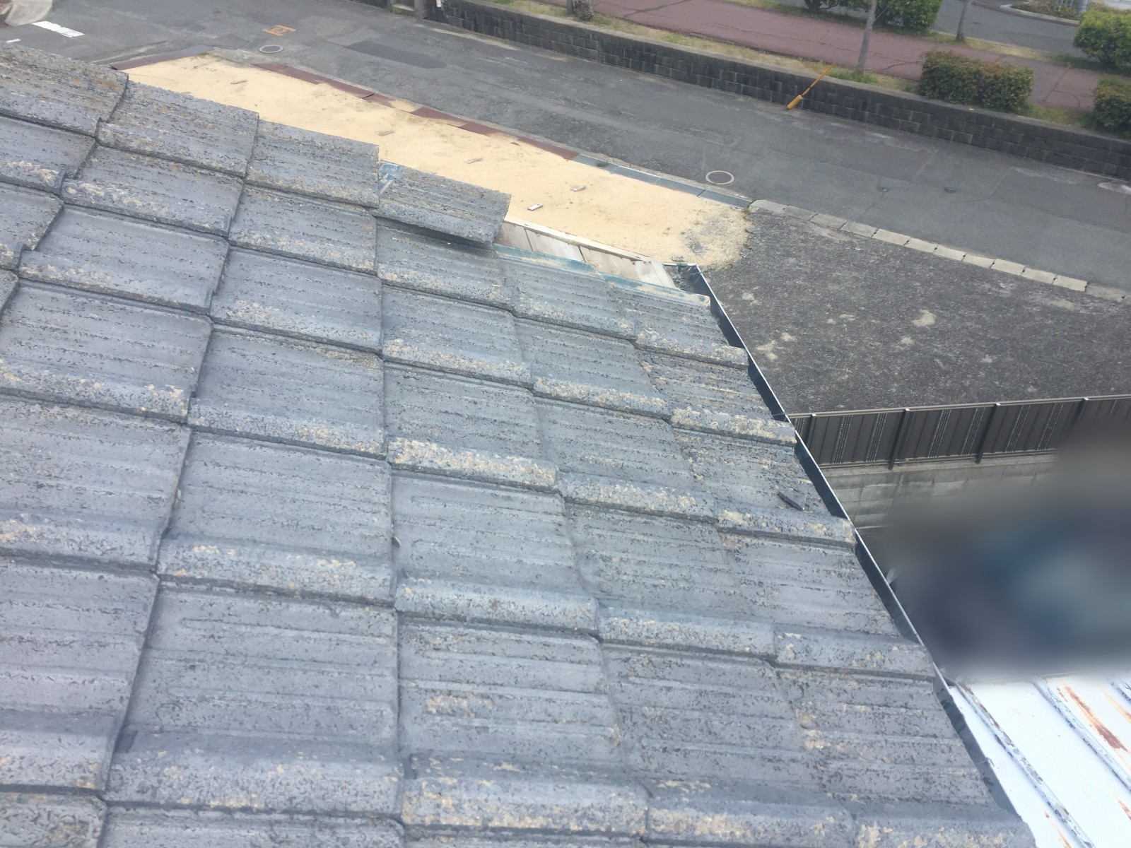 屋根の角でまわりから浮き上がったセメント瓦