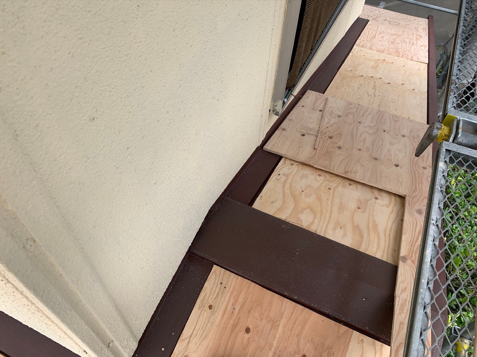 下屋の壁際から張り始めた合板