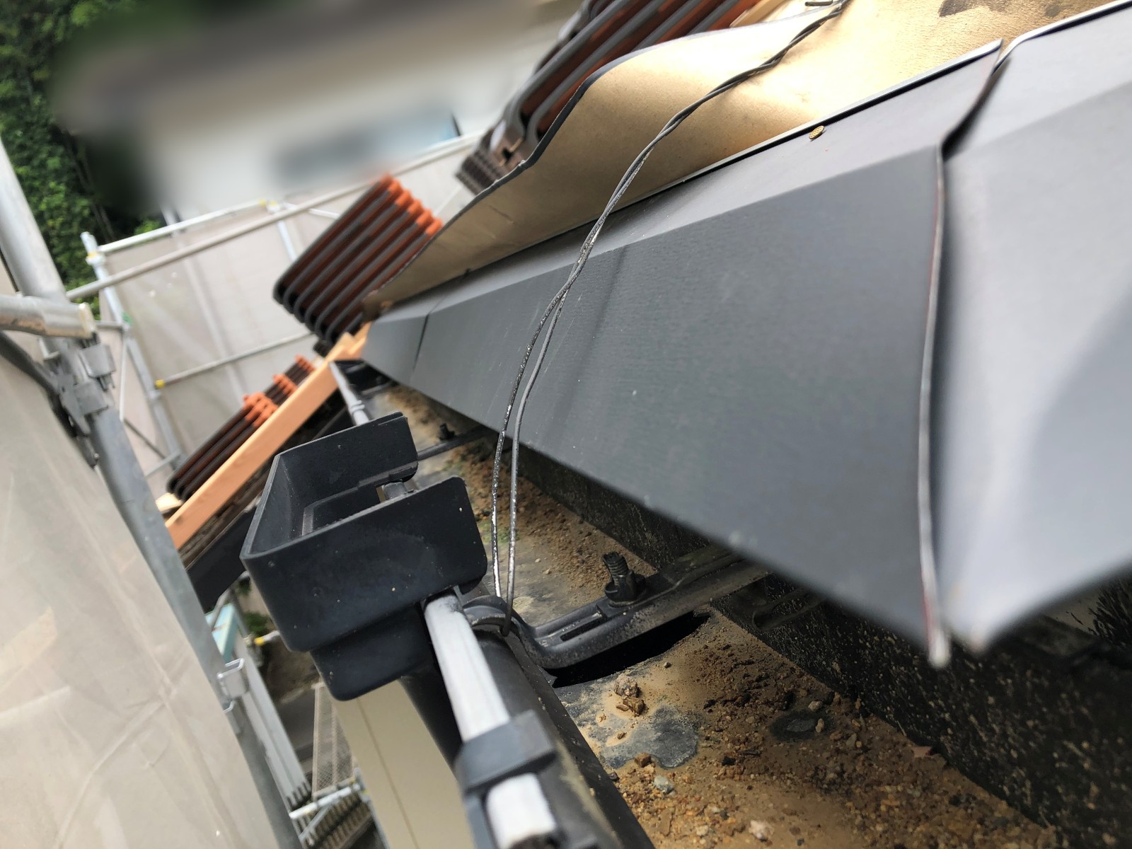 軒先の木材にかぶせた金属の板とすぐ下を通る雨どい