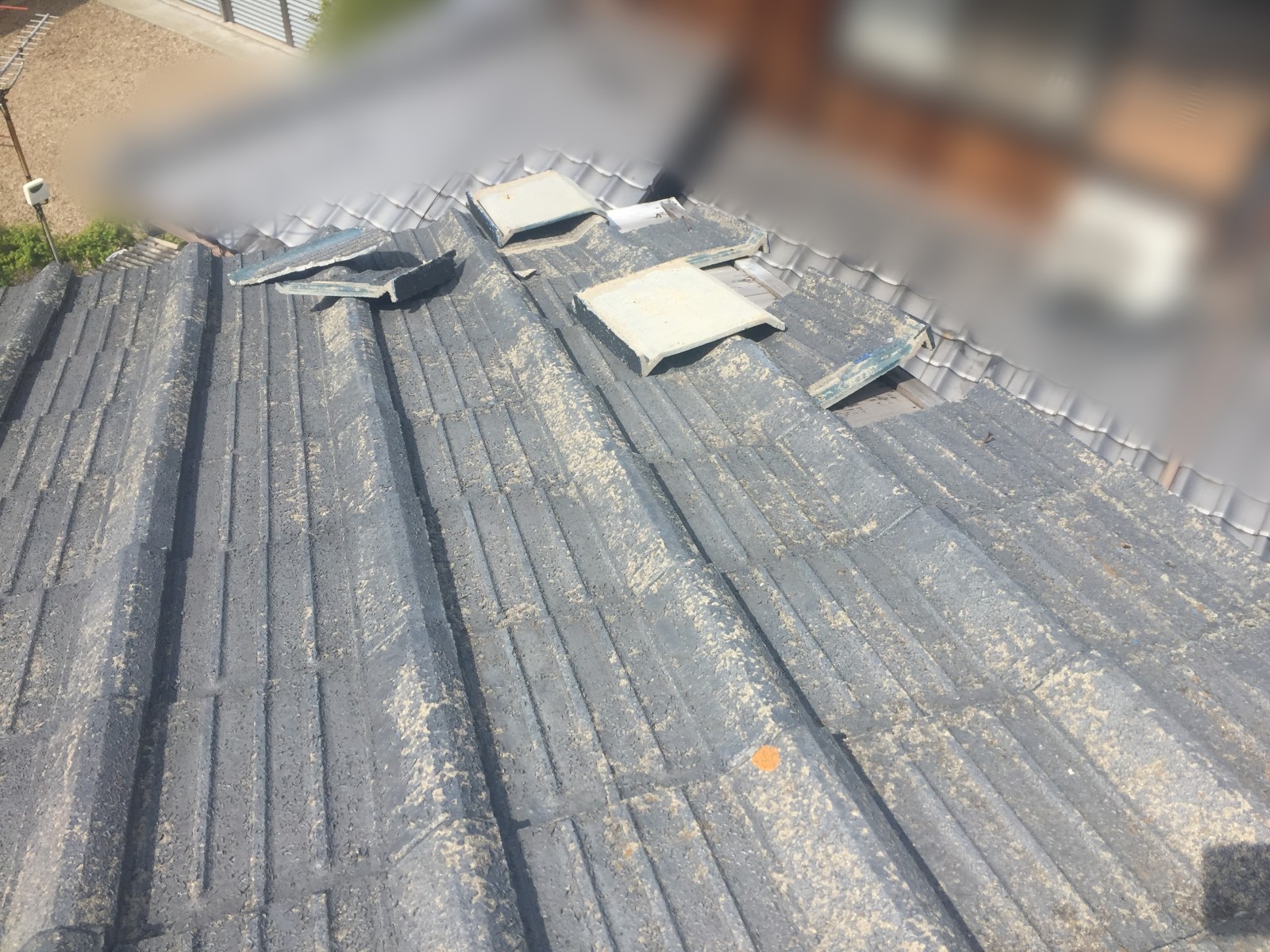 一段低い屋根の上に散らばった瓦のかけら