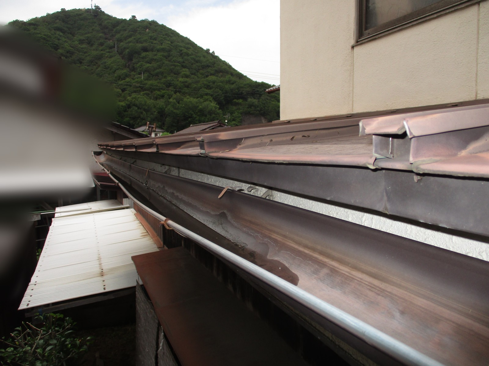 茶色い水の跡が筋のように残る軒樋の底
