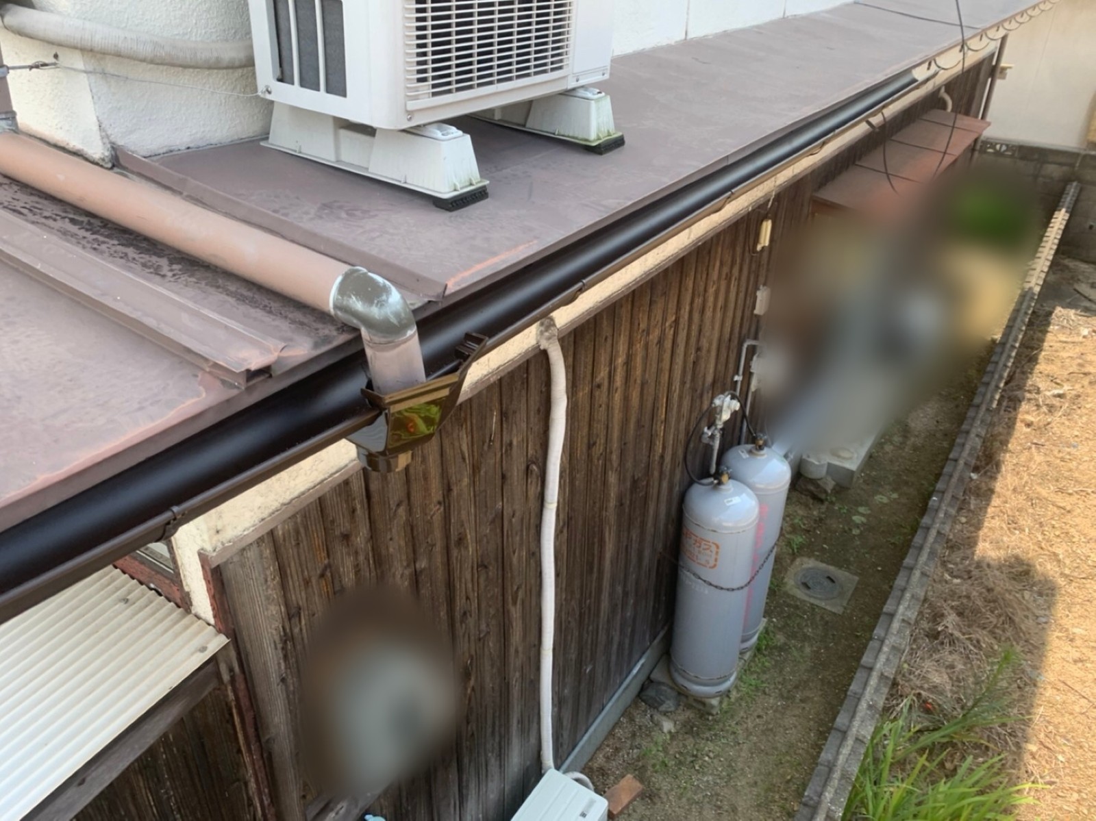 板金屋根の軒先に並ぶ新しい軒樋と集水器
