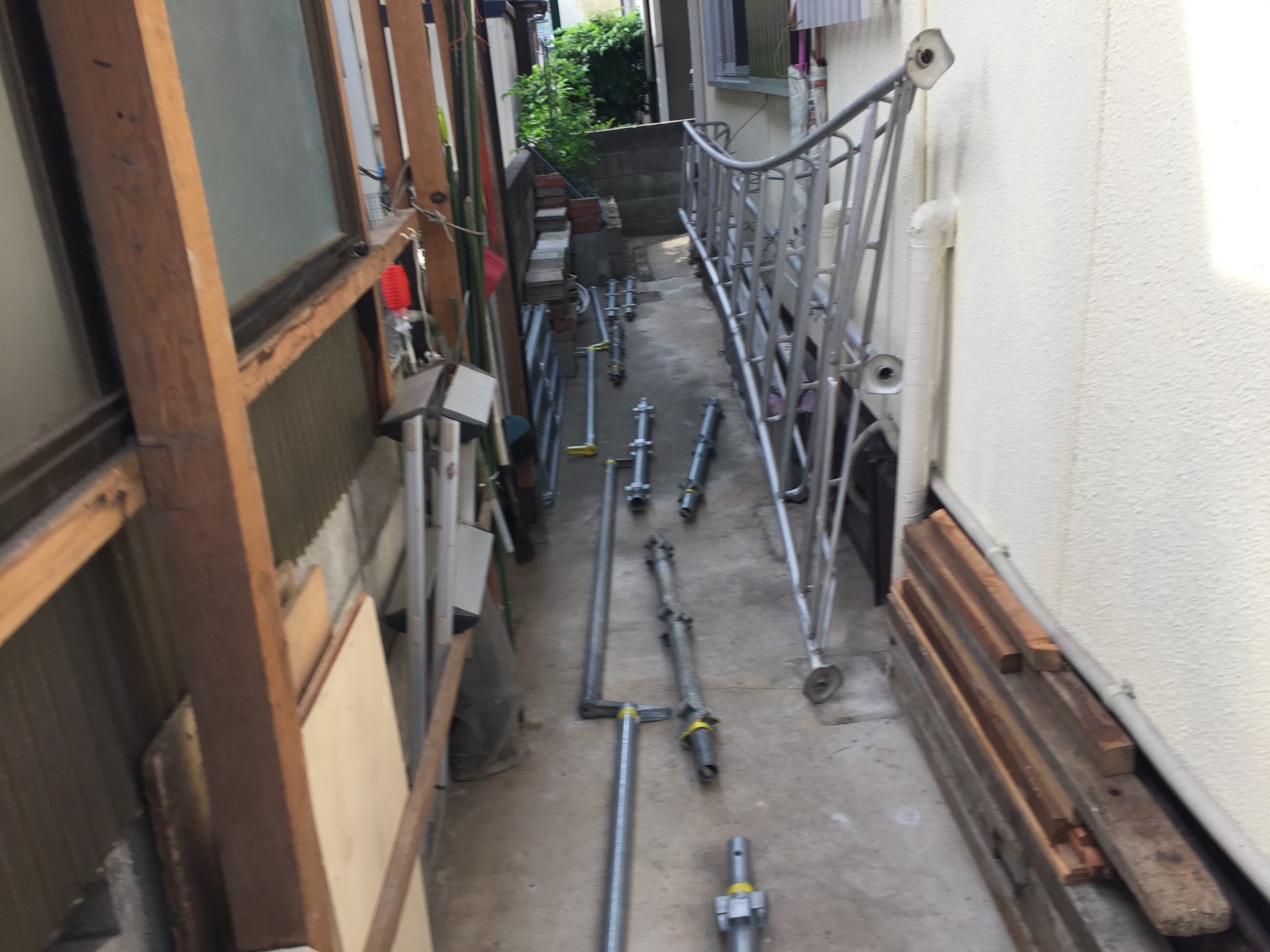 建物と塀の間の狭い通路に運び込んだ足場の部材