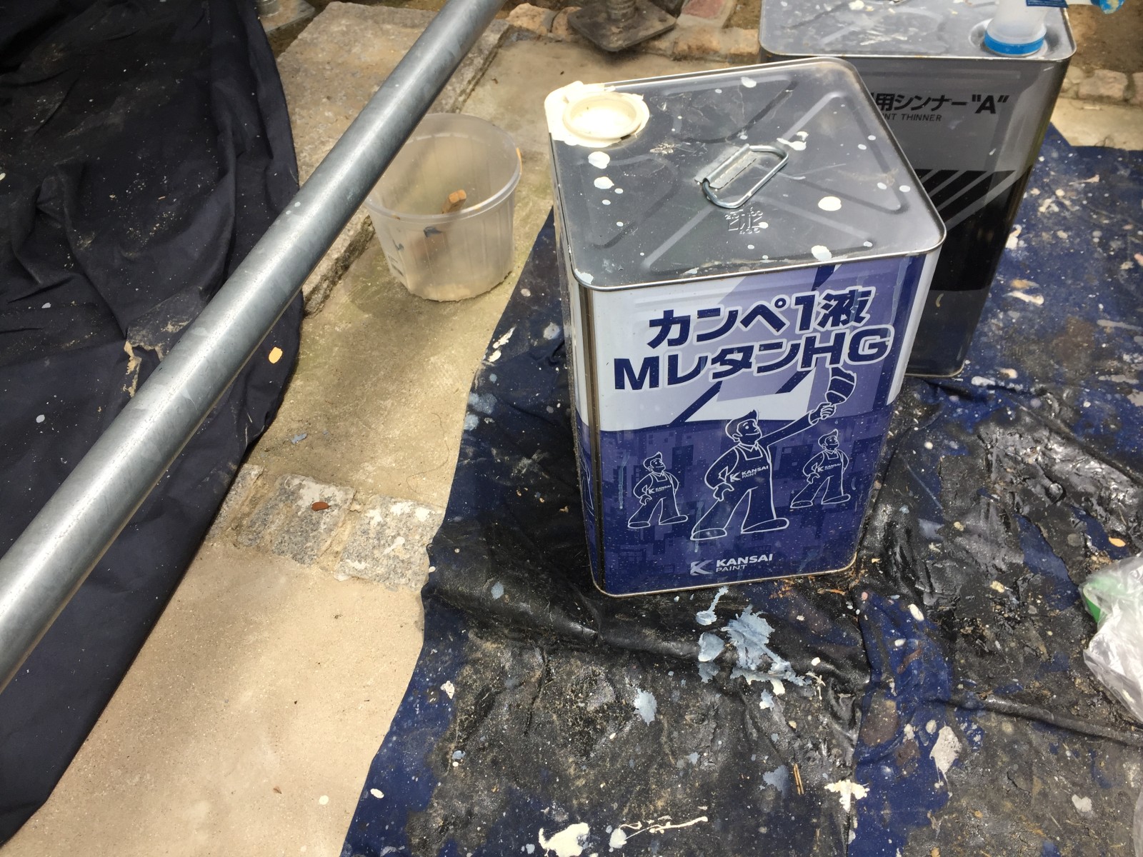 作業場所の足元に敷いた養生シートの上に置いた塗料の缶