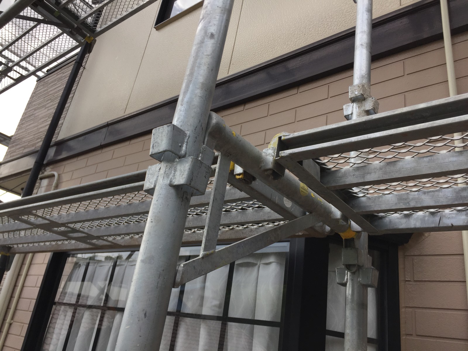 外壁にそって渡した金属の作業床と手すりのパイプ