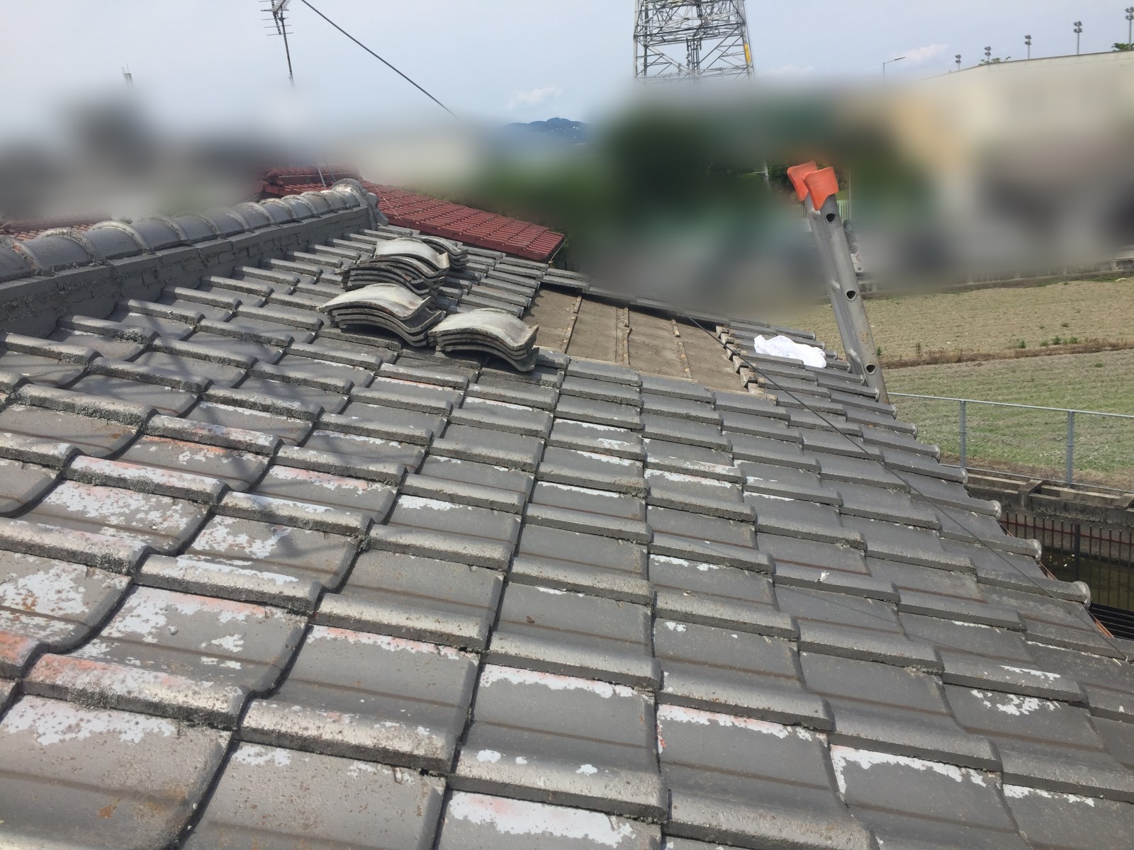 近くに畑が広がる屋根の上に重ねてあるめくった瓦