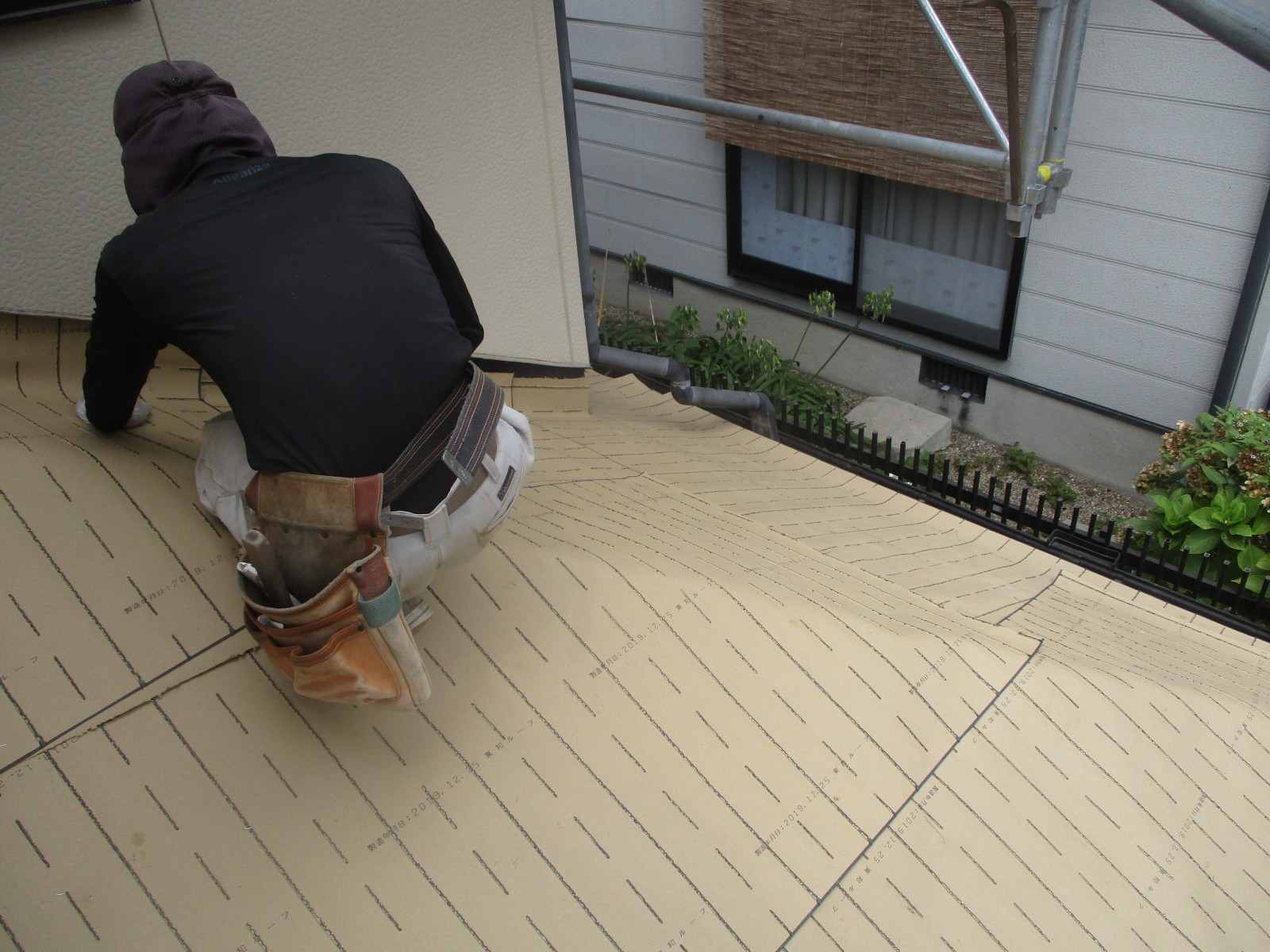 新しい防水紙の上で作業する職人