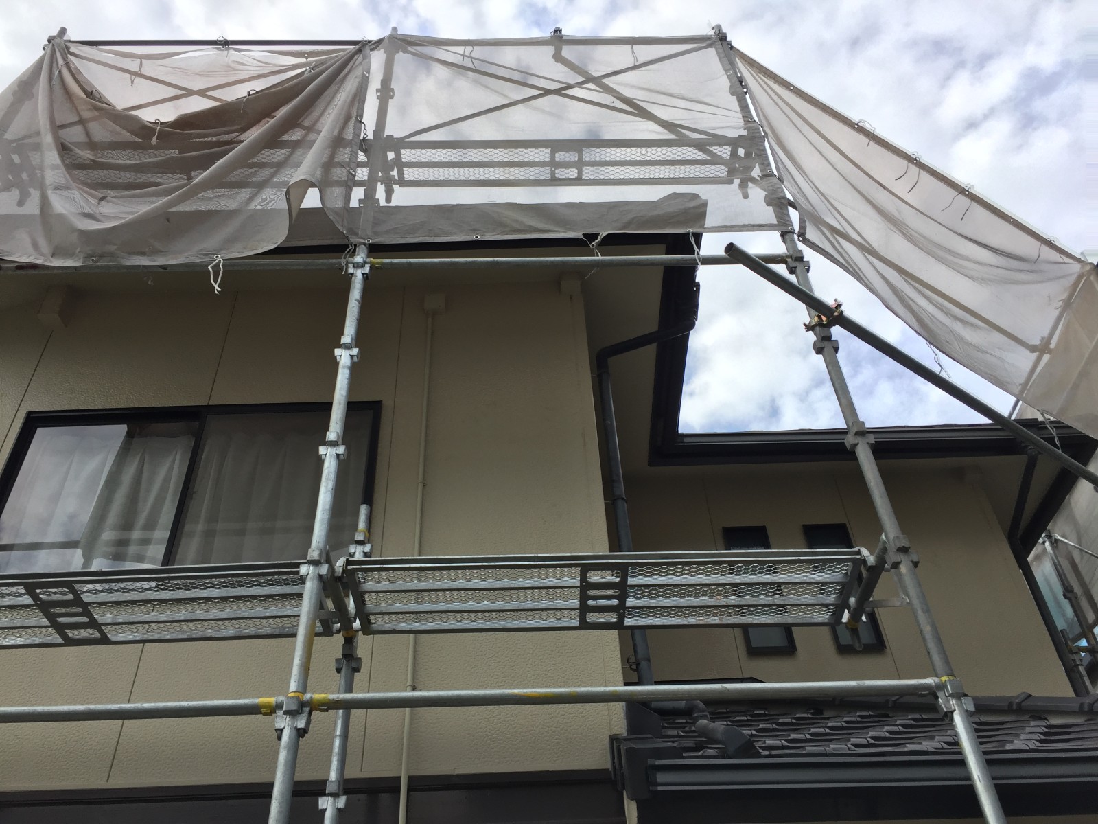 軒先とほぼ同じ高さまで組み上げた足場とネット