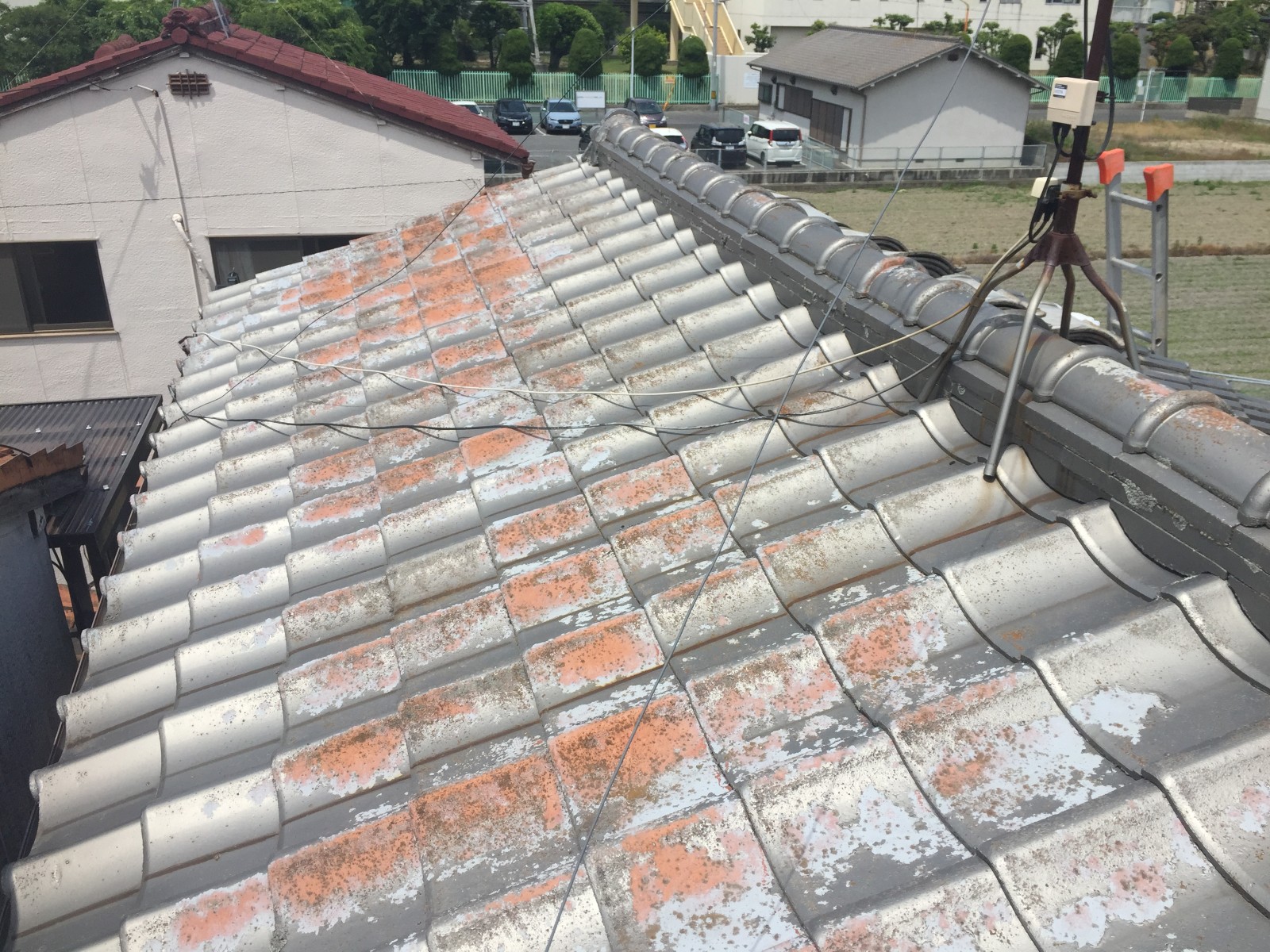 塗装がはがれて地の色がまだらに出たセメント瓦の屋根