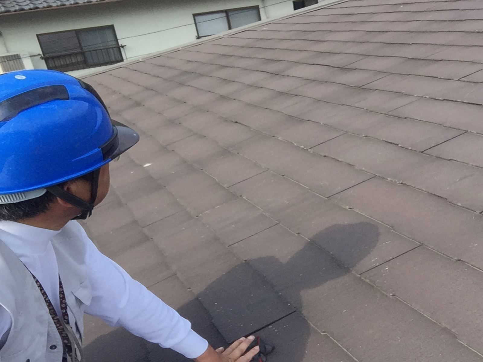ヘルメットを着用したスタッフが屋根へ上がり、スレート屋根全体の状態を安全に点検している様子