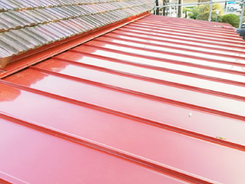 施工後の明るいレッドのルバリウム鋼板タフビーム縦葺き屋根